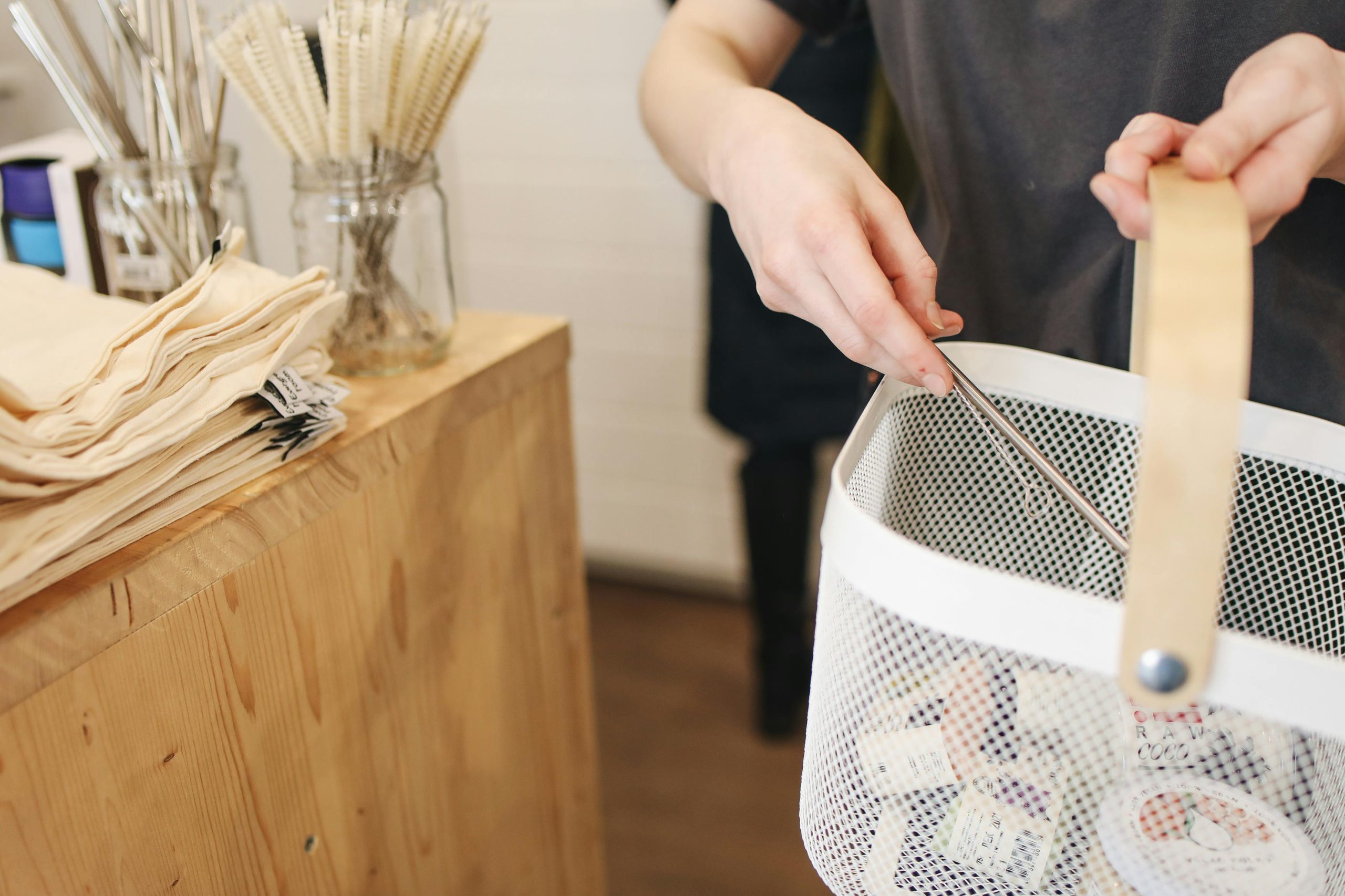 Person shopping sustainably with a reusable basket in an eco-friendly store.