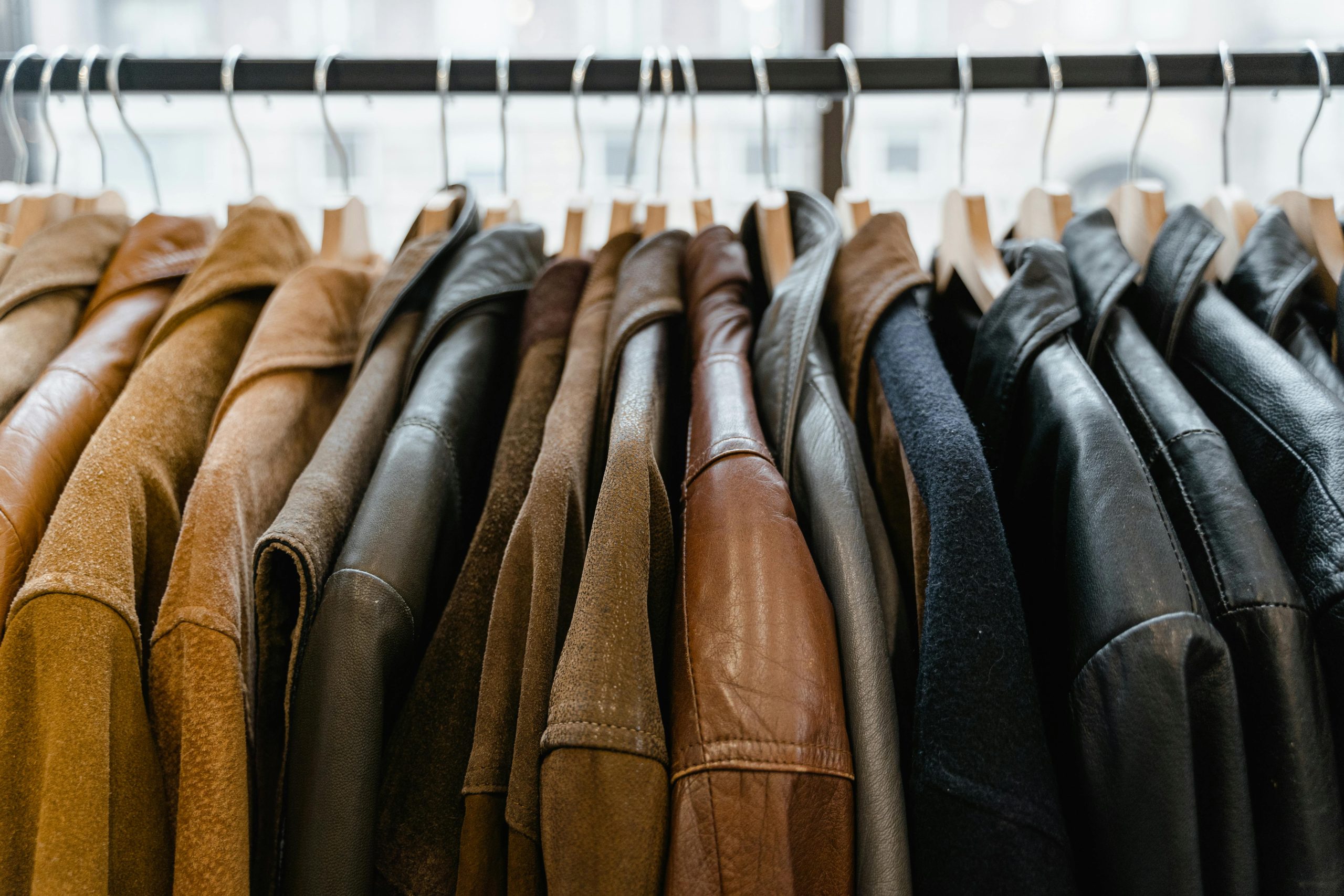 A close-up view of leather jackets hanging neatly on a rack inside a store.